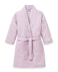 A young girl with blonde hair smiles as she ties the belt on her Kid's Twill Robe in Fleur Blush over a white nightgown.