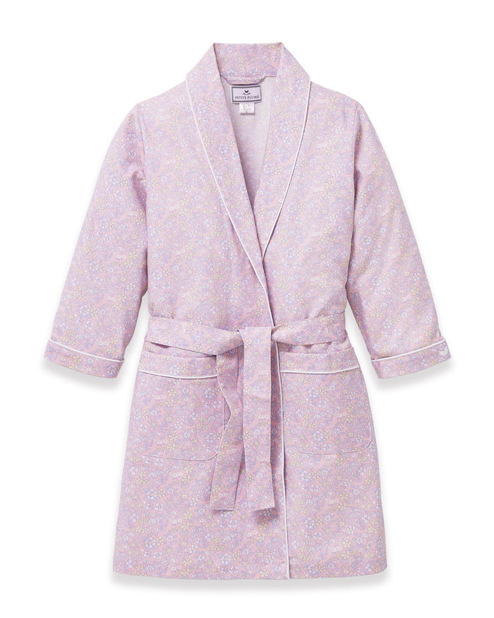 A young girl with blonde hair smiles as she ties the belt on her Kid's Twill Robe in Fleur Blush over a white nightgown.