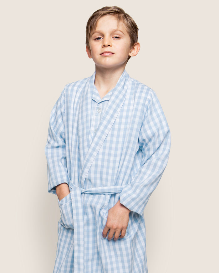 The Kid's Twill Robe in Light Blue Gingham features a soft gingham pattern, long sleeves, shawl collar, front pockets, and a matching belt at the waist for comfort and style.