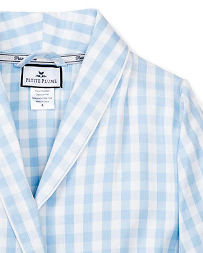 The Kid's Twill Robe in Light Blue Gingham features a soft gingham pattern, long sleeves, shawl collar, front pockets, and a matching belt at the waist for comfort and style.
