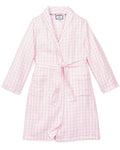 A close-up of Petite Plumes Kids Twill Robe in Pink Gingham shows its soft, textured fabric, reminiscent of classic childrens sleepwear. The robe features a folded cuff with stitched letters and a tied belt across the light pink and white gingham pattern.