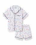 The Kid's Twill Short Set in Literary Lessons features a white base with colorful school-themed prints—pencils, books, and erasers—plus navy piping on the collar, pocket, sleeves, and shorts.