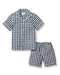 The Kids Pajama Short Set in Navy Gingham by Petite Plume is made from yarn-dyed cotton, featuring a button-down top with a chest pocket and shorts with an elastic waistband for comfort.