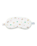 A young girl with long brown hair wears the Kid's Twill Sleep Mask in Good Luck Charms and a matching pajama top featuring rainbows, horseshoes, and clovers, standing against a neutral background.