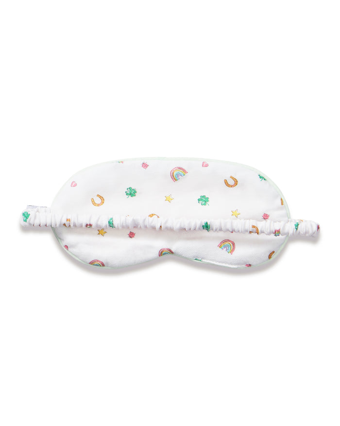 A young girl with long brown hair wears the Kid's Twill Sleep Mask in Good Luck Charms and a matching pajama top featuring rainbows, horseshoes, and clovers, standing against a neutral background.