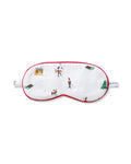 The Kid's Twill Sleep Mask in Holiday Town is a white mask with red trim, decorated with winter scenes of people, a reindeer, a house, a sled, and snowy trees. A small white tag is attached on the right side.