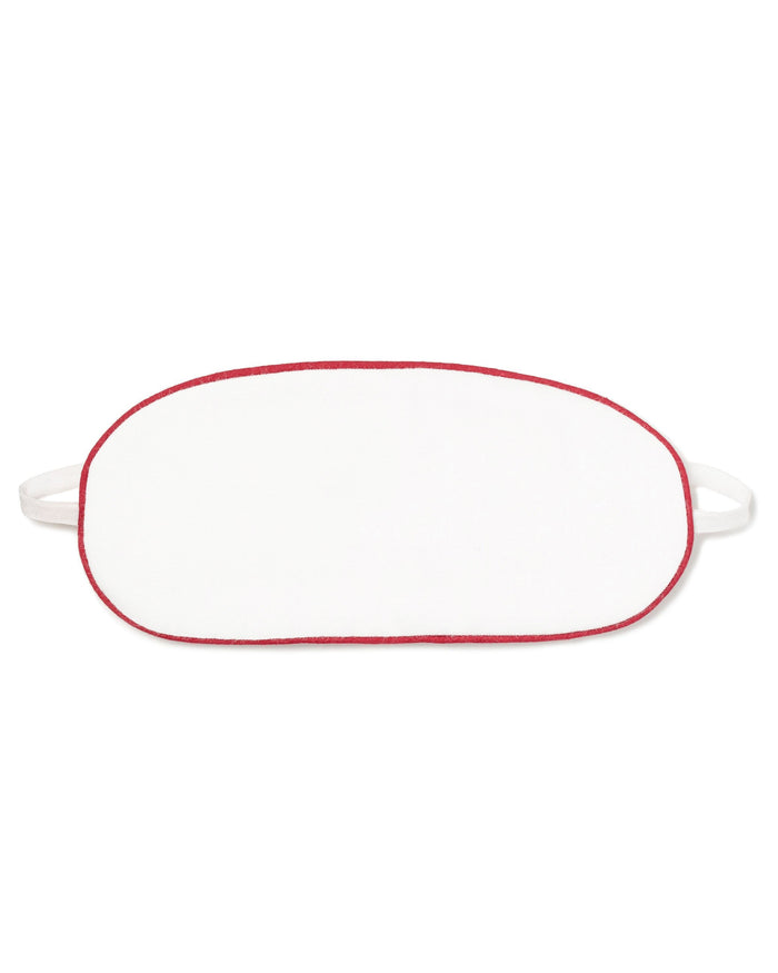 White oval-shaped kid’s twill sleep mask with red piping and two straps, laid flat against a white background.