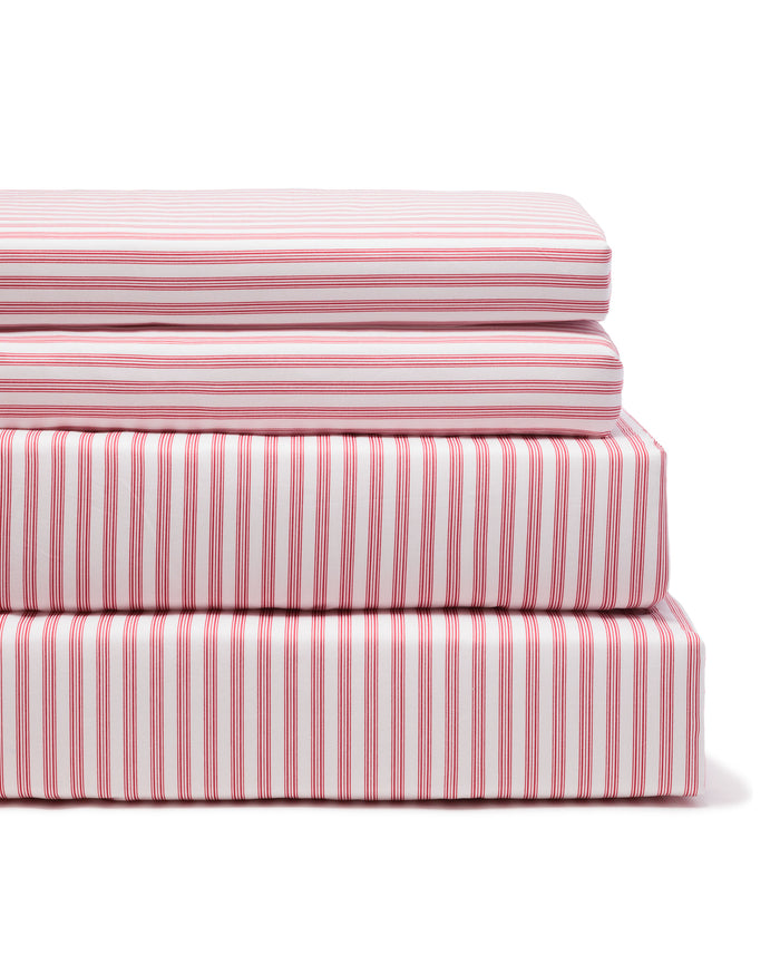 A neatly arranged stack of Petite Plume’s Luxe Premium 100% cotton bed sheets in an antique red ticking pattern features varied percale sheet sizes displaying stripes in diverse orientations against a plain white background.