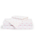 The Luxe Premium Percale Bed Sheets in Blushing Bows feature white sheets with a pink bow pattern, including pillowcases and flat sheets, all folded neatly and displayed on a white background.