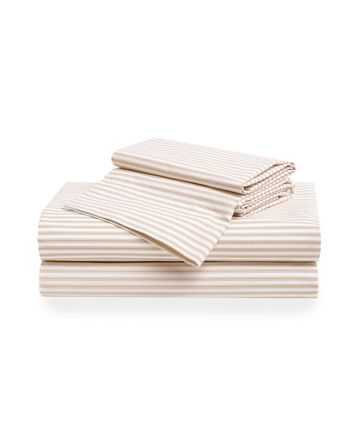 The Luxe Premium Percale Duvet Set in Camel Gingham features two pillows and a folded comforter with a beige and white gingham check pattern, neatly stacked on a white background.