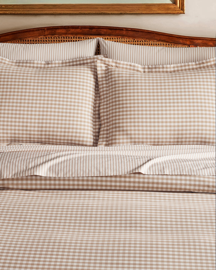 The Luxe Premium Percale Bed Sheets in Camel Ticking feature beige and white stripes and include a flat sheet, fitted sheet, and two pillowcases, all neatly folded and displayed on a white background.