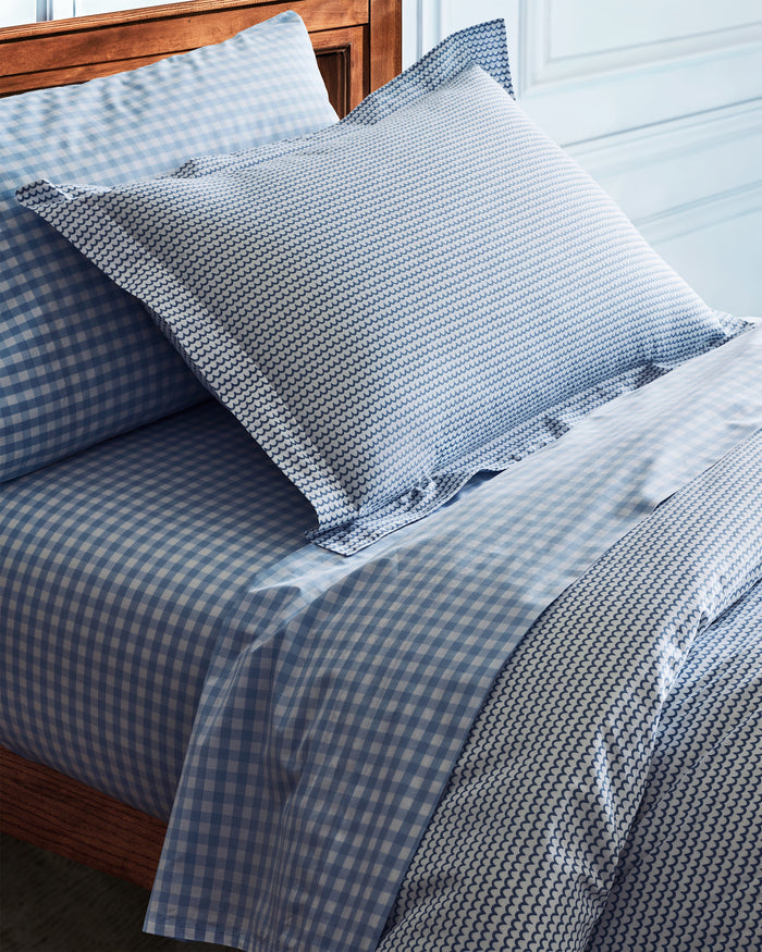 Experience luxury with the Luxe Premium Cotton Light Blue Gingham Bed Sheets by Petite Plume, featuring soft percale sheets and matching pillowcases on a wooden bed frame against a light blue wall.