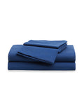 A cozy bed with Luxe Premium Cotton Bed Sheets in Navy by Petite Plume, accented with green garland and a lit candle on the bedside table, creates a festive atmosphere.