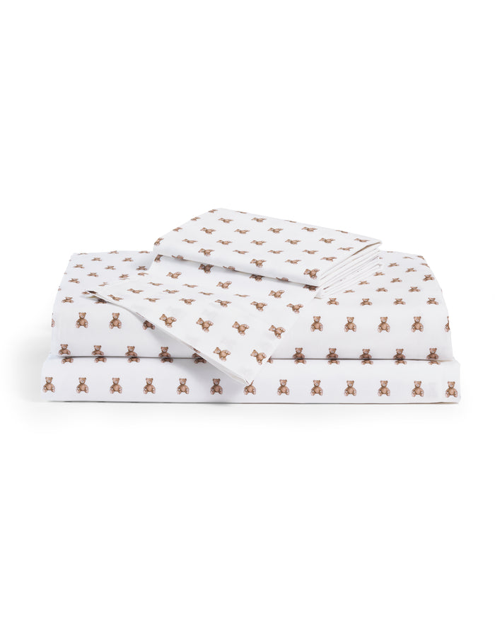 A stack of Luxe Premium Percale Bed Sheets in Teddy Tales, white and neatly folded, showcases a charming repeating pattern of small brown teddy bears.