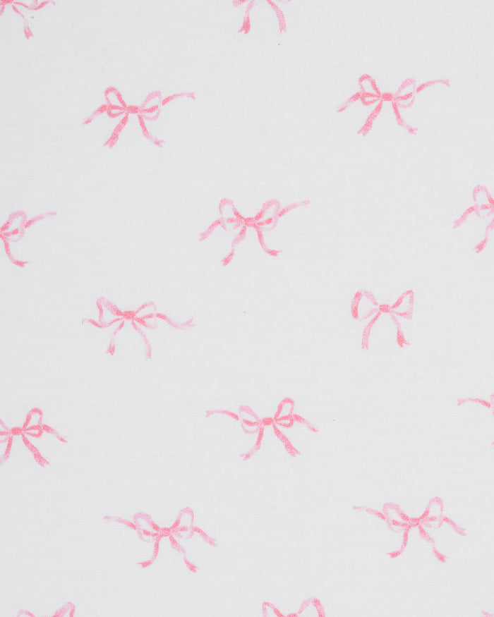 A close-up of the Luxe Premium Percale Crib Sheet in Blushing Bows, featuring a white background with a pattern of small pink ballerinas, neatly wrapped around the corner of a crib mattress.