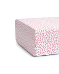 The Luxe Premium Sweethearts Crib Sheet by Petite Plume features ultra-soft, white fabric adorned with small pink heart patterns, evenly distributed for a charming and playful design. The image highlights the corner, showcasing the delightful pattern like cotton percale furniture.