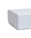 Close-up of Luxe Premium La Mer Crib Sheet by Petite Plume, showcasing an ultra-soft white fabric with a blue wave pattern. The sheet resembles a thick, modern mattress corner and sits on a breathable white backdrop.