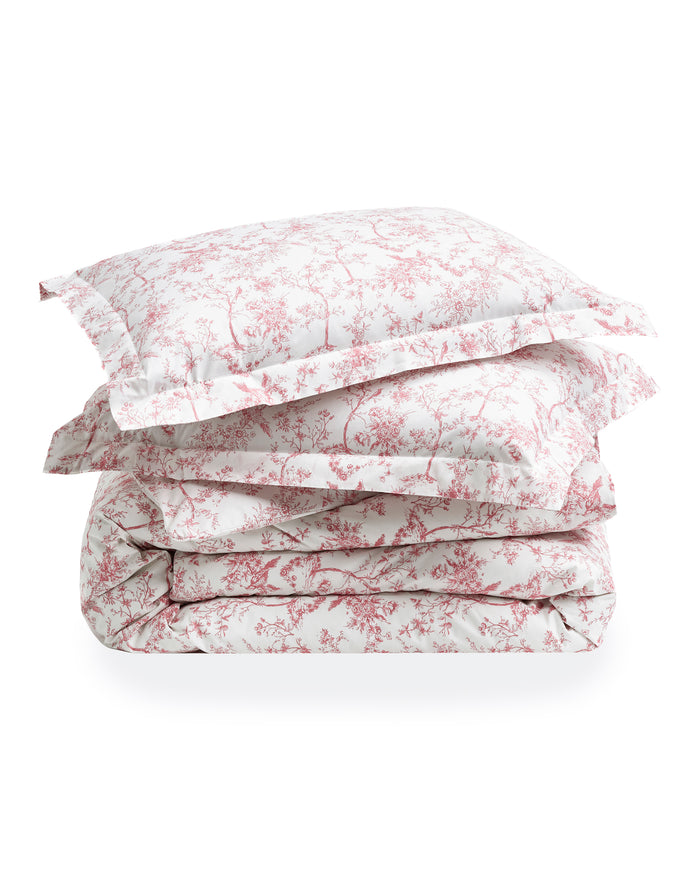 The Luxe Premium Percale Duvet Set in Pink Timeless Toile, featuring a folded duvet cover and two pillowcases with a white background and pink floral pattern, is stacked neatly on a white surface.