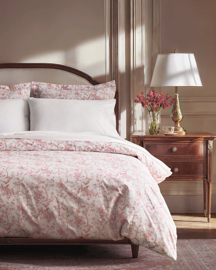 The Luxe Premium Percale Duvet Set in Pink Timeless Toile, featuring a folded duvet cover and two pillowcases with a white background and pink floral pattern, is stacked neatly on a white surface.