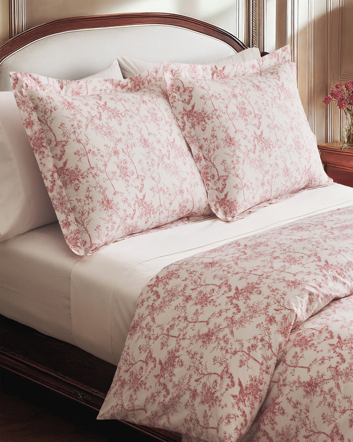The Luxe Premium Percale Duvet Set in Pink Timeless Toile, featuring a folded duvet cover and two pillowcases with a white background and pink floral pattern, is stacked neatly on a white surface.