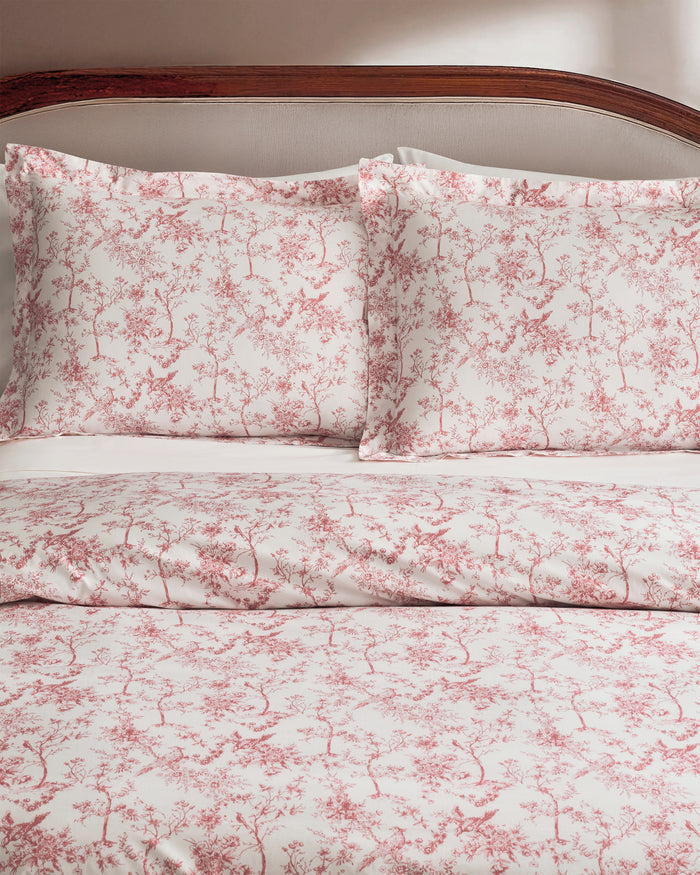The Luxe Premium Percale Duvet Set in Pink Timeless Toile, featuring a folded duvet cover and two pillowcases with a white background and pink floral pattern, is stacked neatly on a white surface.