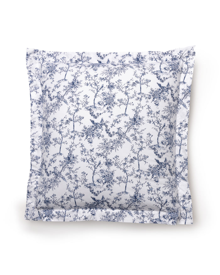 The Luxe Premium Cotton Euro Sham by Petite Plume features a percale square pillow with a white backdrop and intricate blue floral and foliage patterns. Reminiscent of botanical flowers, it displays detailed trees and birds, creating an elegant and classic look.