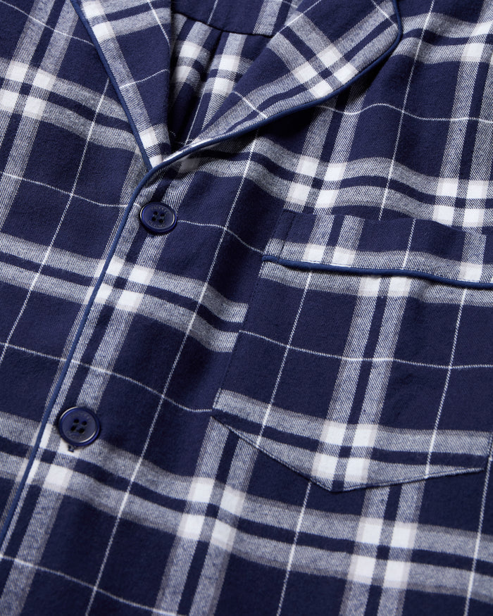 The Men's Brushed Twill Pajama Set in Oxford Tartan includes a two-piece navy and white plaid design with a long-sleeved button-up shirt featuring a chest pocket and matching drawstring pants.