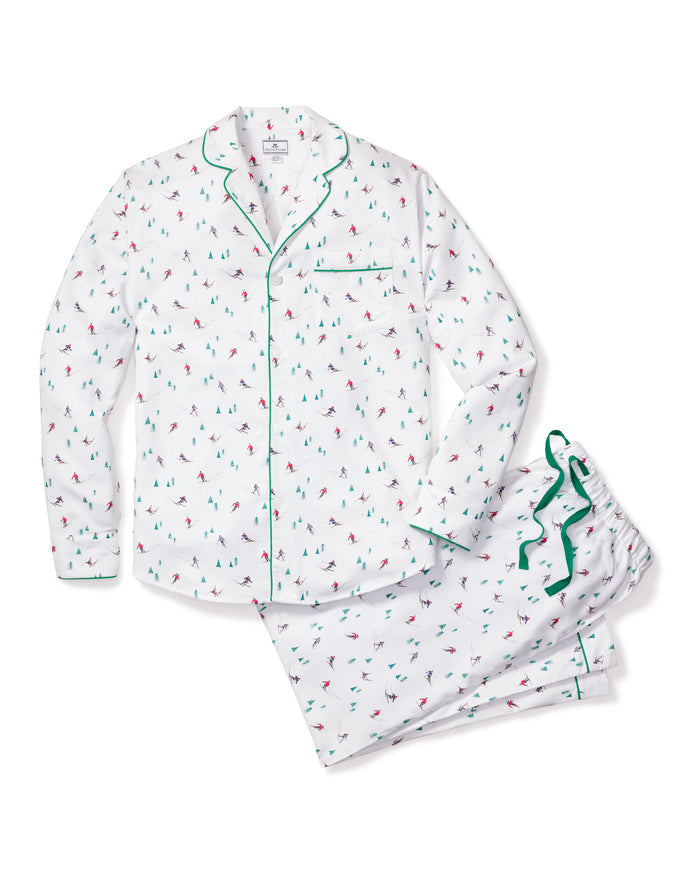 The Petite Plume Mens Flannel Pajama Set in Après Ski is crafted from 100% cotton, showcasing a white fabric with green piping and a vibrant small sailboat pattern. It includes a pocketed button-up shirt and matching pants, offering comfort for a cozy nights sleep.