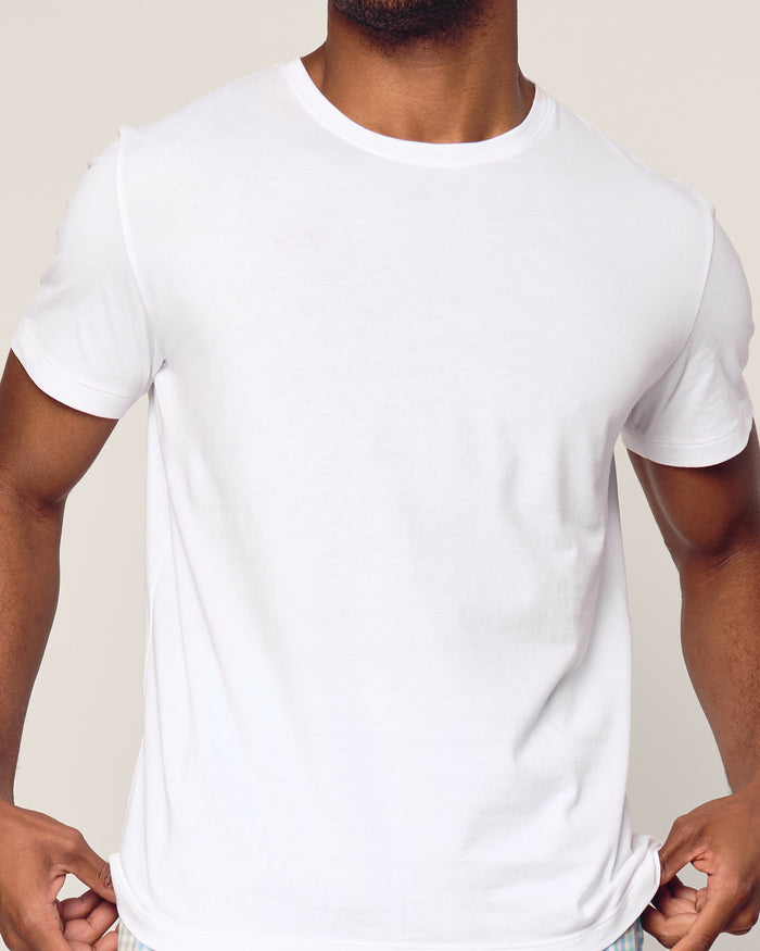 A person in a Mens Pima Crew Neck Short Sleeve Top by Petite Plume, showcasing the soft jersey knit against a neutral background. The focus is on their upper torso with slightly bent arms, highlighting the simple design and fit, reminiscent of luxurious pajamas in comfort and ease.