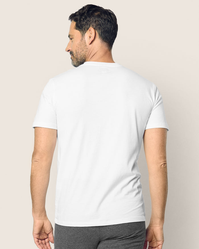 A man with short dark hair is seen from the back, wearing a Petite Plume Mens Pima V-Neck Top in white and gray pants, standing against a neutral background.