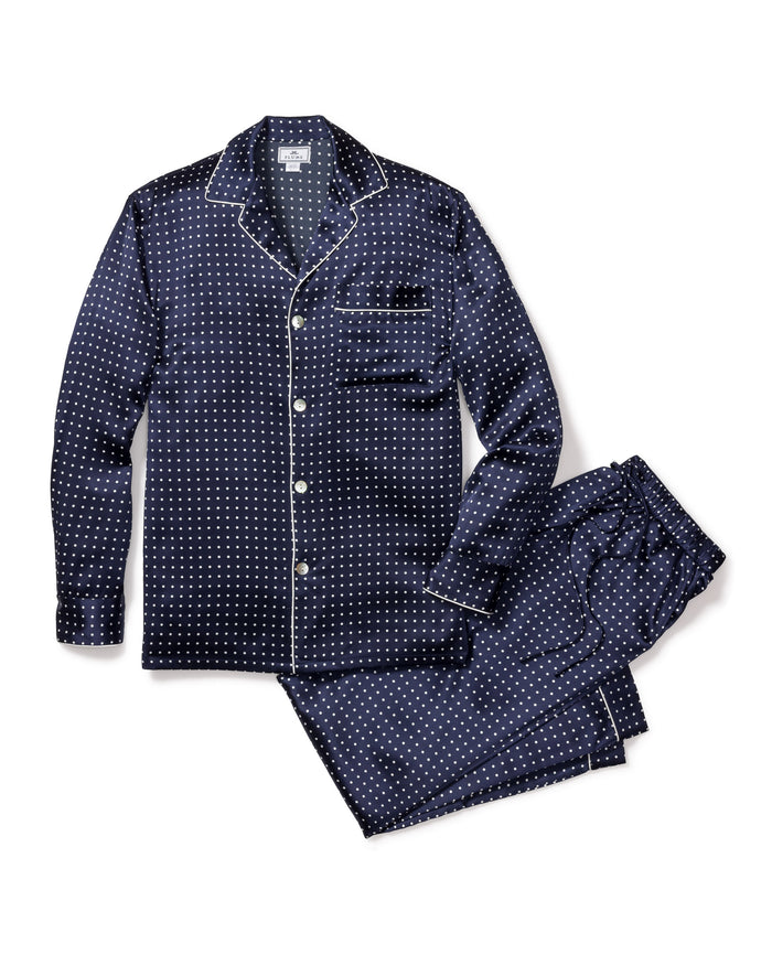 The Mens Silk Pajama Set in Navy Polka Dot by Petite Plume is crafted from machine-washable silk, featuring a dark blue set with white dots. The top has long sleeves, a collar, and a pocket with white piping. Loose-fitting pants with an elastic waistband complete the set on a white backdrop.