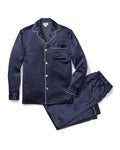 The Mens Silk Pajama Set in Navy Polka Dot by Petite Plume is crafted from machine-washable silk, featuring a dark blue set with white dots. The top has long sleeves, a collar, and a pocket with white piping. Loose-fitting pants with an elastic waistband complete the set on a white backdrop.