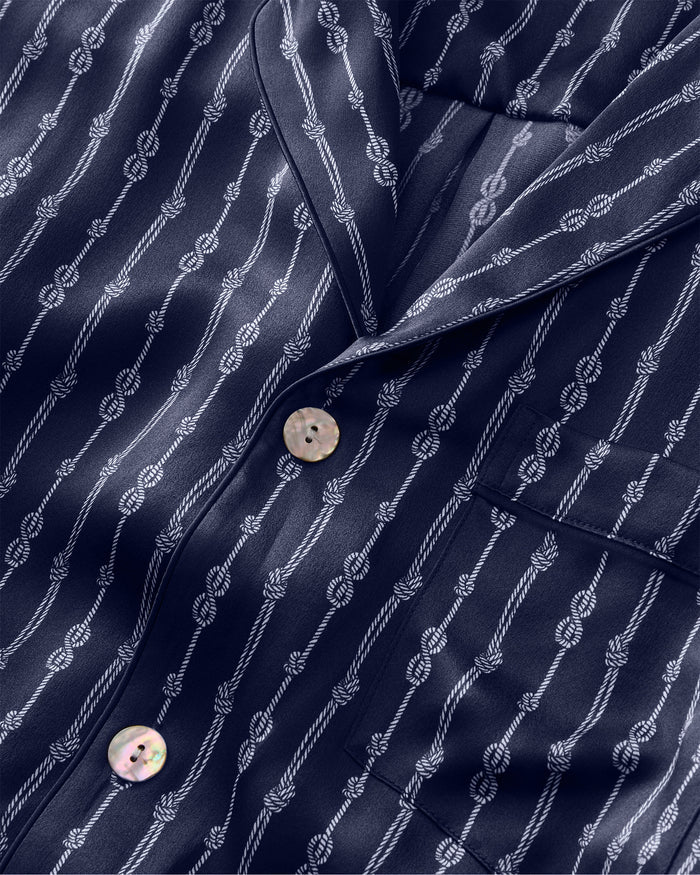 Close-up of the Men’s Silk Pajama Short Set in Nautical Knots, featuring a navy blue shirt with white vertical rope patterns, white buttons, and a front pocket.