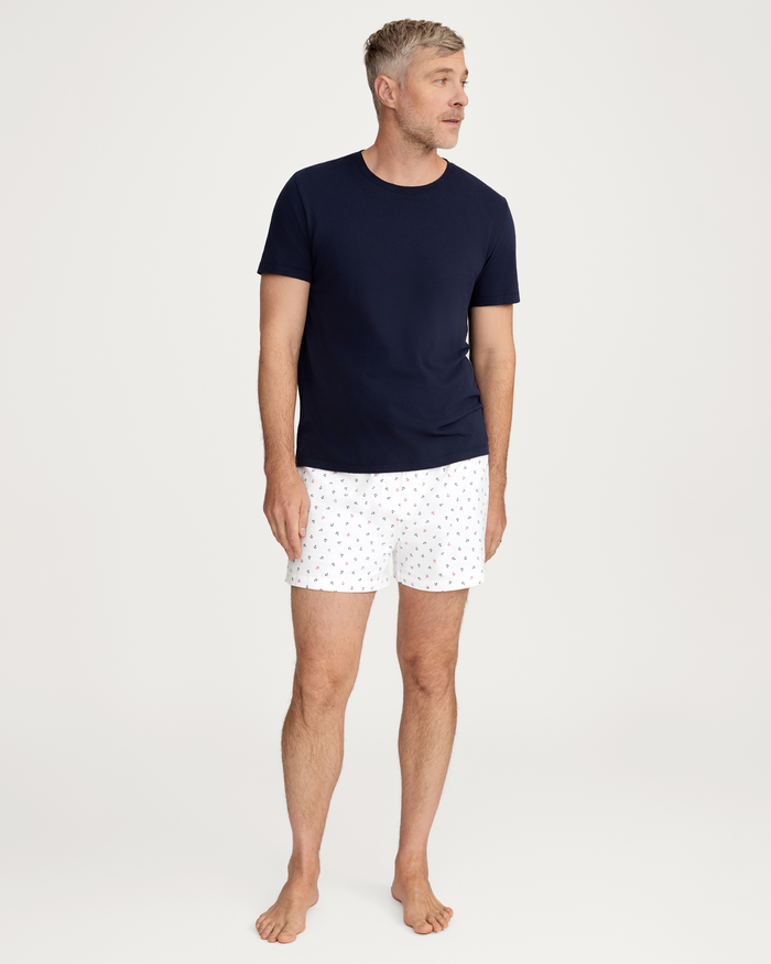 A man stands barefoot, wearing a navy short-sleeve t-shirt and a pair of Men’s Twill Boxers in the Anchors Away pattern from the 3 Pack, against a plain white background.
