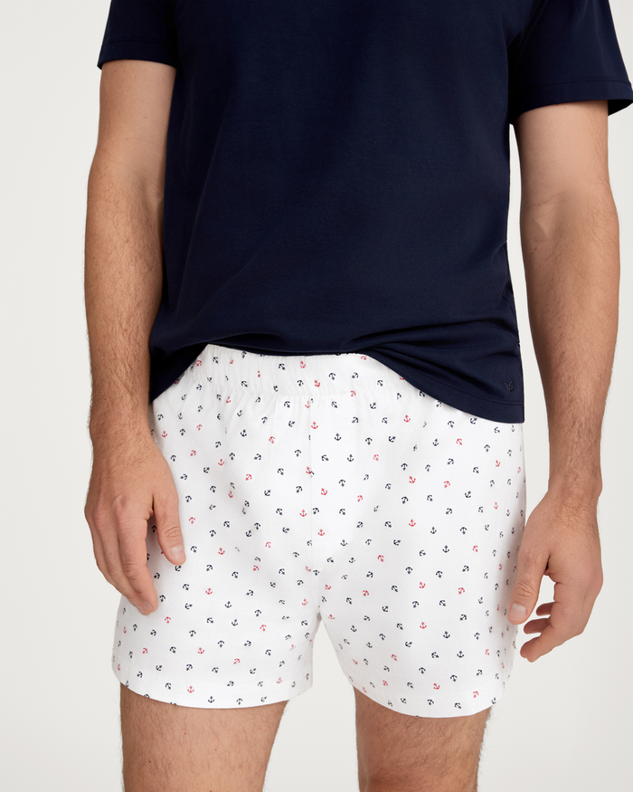 A person is shown from the torso to the upper legs, wearing a navy T-shirt and the Anchors Away print boxer shorts from the Men’s Twill 3 Pack Boxers (Coastal Stripe, Anchors Away, and Navy), against a plain background.