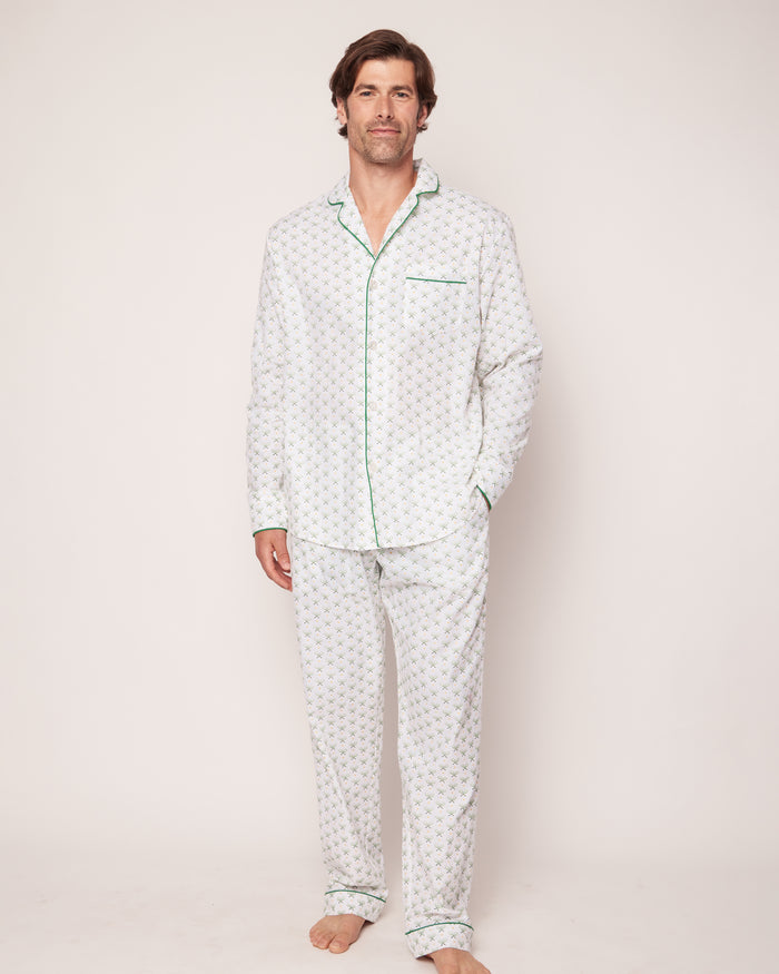 A man stands barefoot on a plain background, wearing Petite Plumes Mens Twill Pajama Set in Match Point. The set features a tennis print with green piping and is crafted from high-quality cotton, including a long-sleeve top and pants. He faces forward in a casual pose.