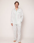 A man stands barefoot on a plain background, wearing Petite Plumes Mens Twill Pajama Set in Match Point. The set features a tennis print with green piping and is crafted from high-quality cotton, including a long-sleeve top and pants. He faces forward in a casual pose.