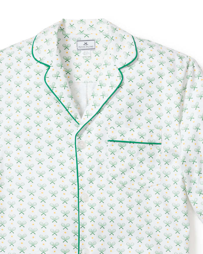 The Mens Twill Pajama Set in Match Point by Petite Plume features a white cotton top with green piping, a tennis print of rackets and yellow balls, and is designed for comfort with a collar, button-down front, and chest pocket.