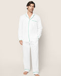 A person is barefoot against a plain background, wearing the Petite Plume Mens Twill Pajama Set in white with green piping. Crafted from high-quality cotton, it features a button-up long-sleeve top and matching pants.#Color_White with Green Piping