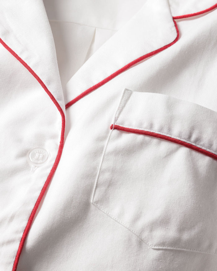 The Petite Plume Mens Twill Pajama Set in White with Red Piping features 100% cotton fabric, neatly pressed with visible buttons. This simple yet elegant design offers luxury sleepwear vibes, perfect for both formal and casual wear.