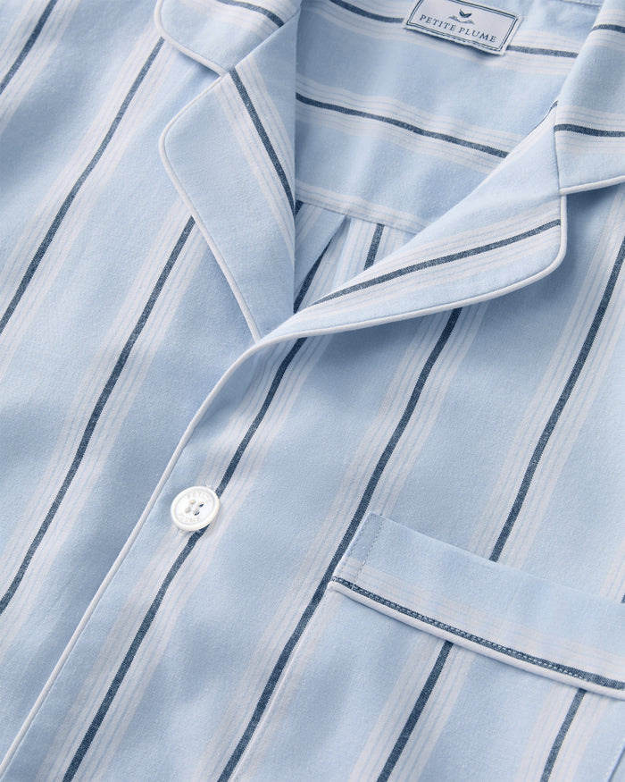 Close-up of the Men’s Twill Pajama Short Set in Coastal Stripe, featuring a light blue and white striped top with a chest pocket, white button, and a notched collar. The label inside the collar reads PETITE PLUME.