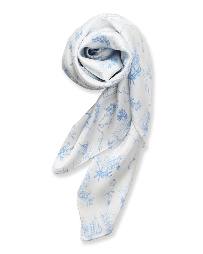 The Petite Plume x Eden Rock Blue Reverie Silk Scarf features delicate blue floral and botanical patterns on white silk, shown loosely folded on a plain white background.