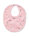 The Petite Plume x Eloise Baby Pima Bib in Eloise Adventures features pink fabric with white polka dots, playful black-and-white drawings, whimsical motifs, a scalloped edge, and a convenient snap closure at the neck.