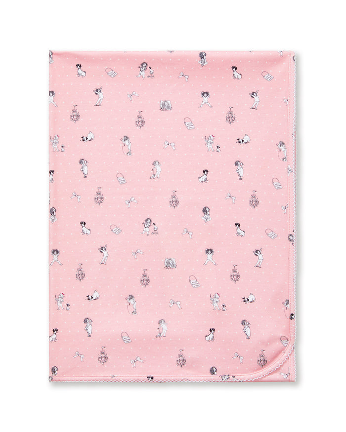 The Petite Plume x Eloise Baby Pima Blanket in Eloise Adventures features a pink fabric with playful girl, dog, and chair illustrations and a neatly stitched edge, displayed flat.