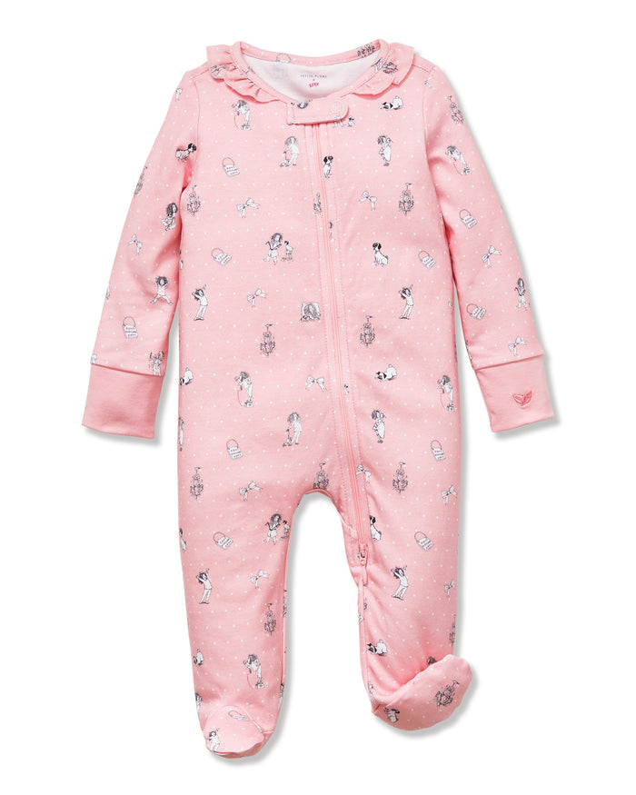 The Petite Plume x Eloise Baby Pima Romper, featuring a pink design with ruffles and playful prints, is displayed alongside the Eloise Hardcover Children’s Book.