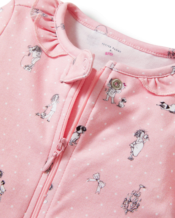 The Petite Plume x Eloise Baby Pima Romper, featuring a pink design with ruffles and playful prints, is displayed alongside the Eloise Hardcover Children’s Book.