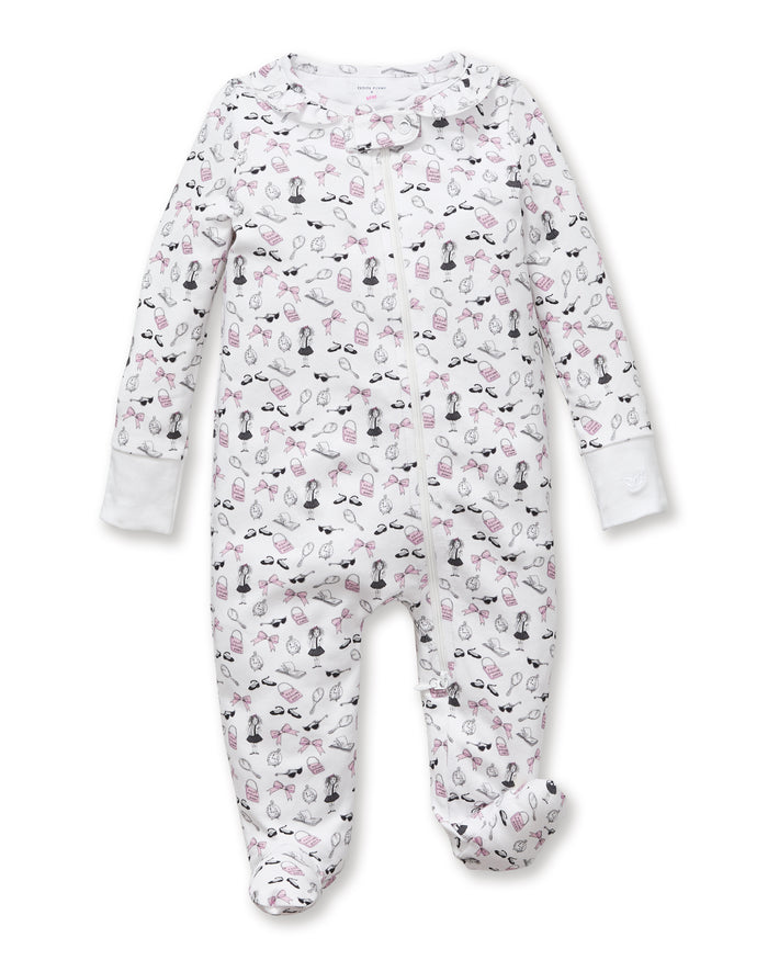 The Petite Plume x Eloise Baby Pima Romper in Eloise Suite Soireé is a white, long-sleeved onesie with a zipper and an all-over print of cartoon dogs, bones, leashes, and paw prints in pink, black, and gray.