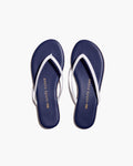 A pair of Petite Plume x TKEES Lily Sandals in navy with white straps, photographed from above on a white background. "THE PETITE PLUME" is printed in gold on the insoles.