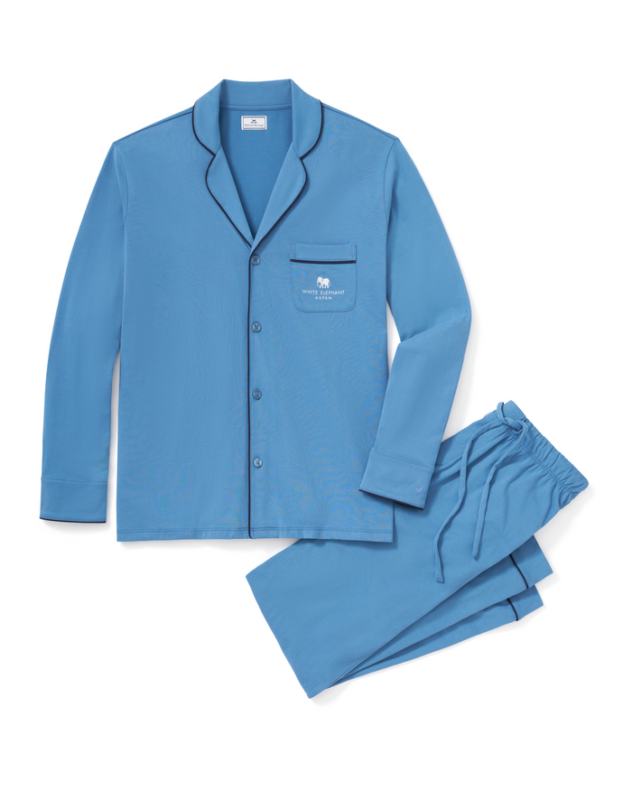 The Petite Plume x White Elephant Men’s Pima Pajama Set, featuring a light blue long-sleeve button-up top with a chest pocket and matching pants, both accented with dark blue piping trim, is neatly arranged on a white background.
