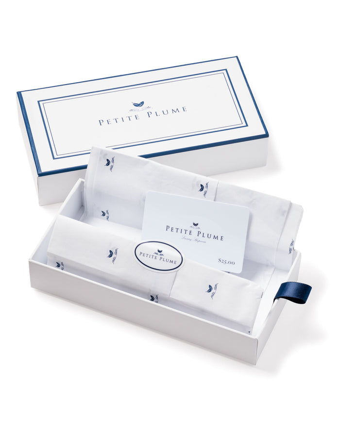 A Petite Plume gift box featuring white fabric with small blue designs, navy trim, and a navy ribbon pull tab, includes a Petite Plume Physical Gift Card. Perfect as a gift choice.